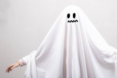 Cadılar Bayramı. Çocuk beyaz bir çarşaf, bir bez ile kaplıdır. boyalı siyah gözler ve bir yüz yapar,