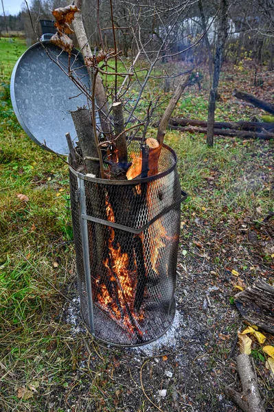 Eski bir çöp kutusunda yanan bahçe öğütücüsü. — Stok fotoğraf