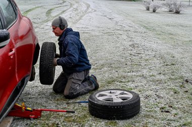 Orta yaşlı bir adam evde lastik değiştiriyor.