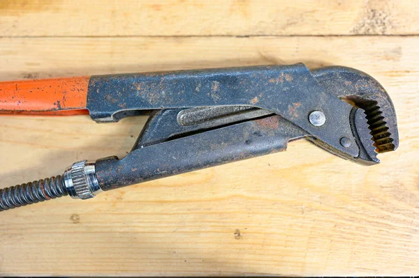 Open pipe wrench lying on wooden workingbench — Stock Photo, Image