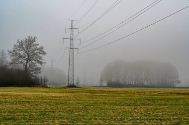Tarım alanlarının üzerindeki güç hattı sisli bir sabah