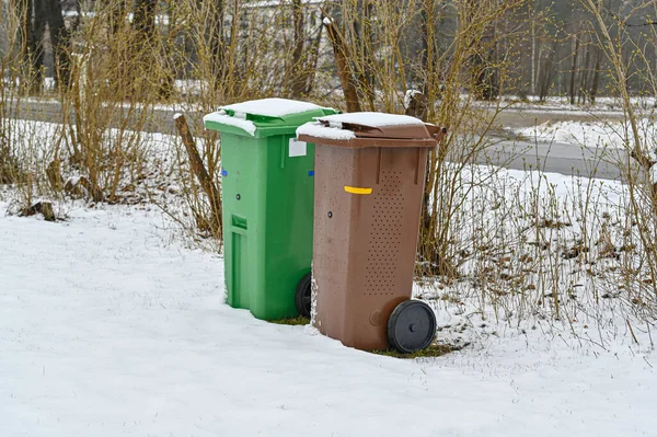 garbage bins in brown and green and snow