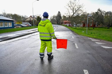 Adam kırmızı bayrakla yol çalışması yapıyor.