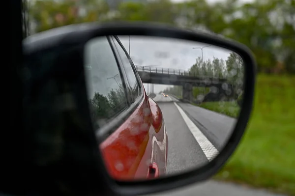 looking through side mirror at bridge over highway