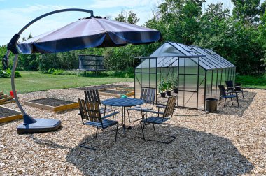 Sera masası ve bahçede güneşlik sandalyeler.