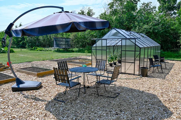 Sera masası ve bahçede güneşlik sandalyeler.