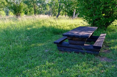 Tahta masa ve dinlenme alanındaki banklar.