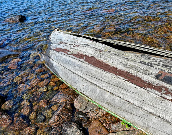 Сломанная деревянная лодка на пляже из камней — стоковое фото