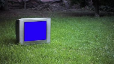 Old Television with Blue Screen in the Grass. Zoom In. You can replace blue screen with the footage or picture you want. You can do it with Keying effect in After Effects or any other video editing software (check out tutorials on YouTube).  