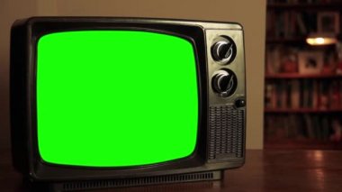 Oturma odasında yeşil ekranlı TV seti. Yakınlaştır. Yeşil ekranı istediğin görüntüyle ya da resimle değiştirebilirsin. Sonraki Efektler ya da herhangi bir video düzenleme yazılımında Keying efekti ile yapabilirsiniz (YouTube 'daki derslere bakın). 