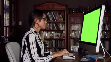 Ofiste Bilgisayar Yeşil Ekran 'la çalışan İş kadını. Yeşil ekranı istediğin görüntüyle ya da resimle değiştirebilirsin. AE 'de tuşlama efektiyle yapabilirsiniz..  