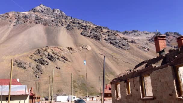 阿根廷国旗自豪地在安第斯山脉的一个小村庄Las Cuevas的旧火车站上飘扬 Resolution — 图库视频影像