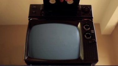 Man Hand, VHS 'yi VCR' a ve Eski TV 'yi Yeşil Ekran' a yerleştiriyor. Yeşil ekranı istediğin görüntüyle ya da resimle değiştirebilirsin. Sonraki Efektler ya da herhangi bir video düzenleme yazılımında Keying efekti ile yapabilirsiniz (YouTube 'daki derslere bakın).  