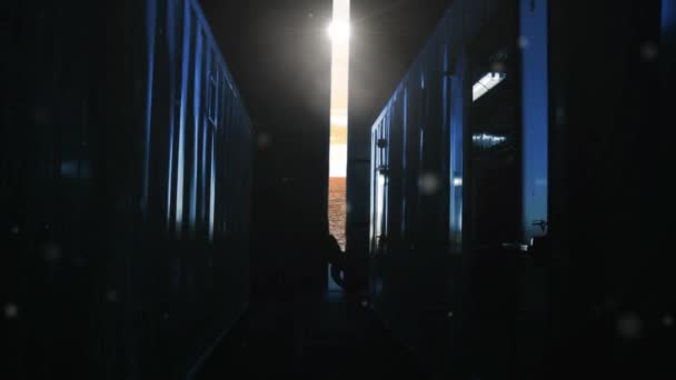 日の出にコンテナ倉庫の金属ドアを開ける男 背景のオレンジ色の空と海 — ストック動画