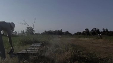 Apiary 'de Kovan Çerçevesini inceleyen bir arı yetiştiricisi, Arı Kovanı Çerçevesi ve Arı İçicisi' ni tutan bir adam, Kovan içen bir arı yetiştiricisi.. 