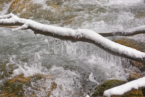 奔腾的溪水上方的冰柱 — 图库照片