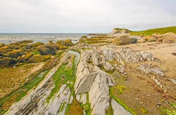 Rotsen en zand op een Remote kust — Stockfoto