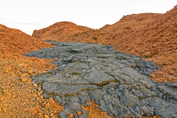 Schwarzer Lavastrom auf roter Vulkanasche — Stockfoto