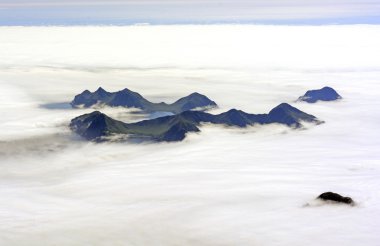 Aerial View of an Island Poking Through Ocean Fog clipart