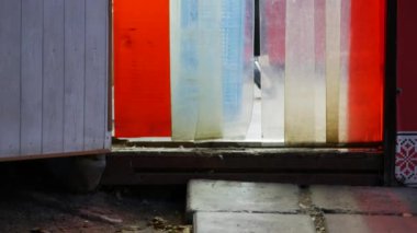 Yüz maskeli müşteriler akşam küçük bir marketten çıkıyorlar. PVC soyunma perdesi