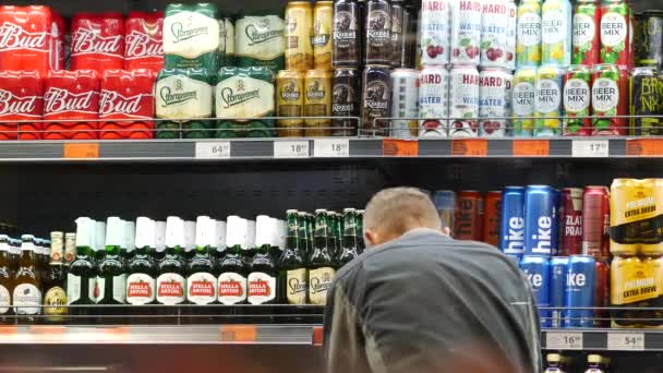 Facet nosi maskę na twarzy w supermarkecie ATB. Półki z piwem w puszkach — Wideo stockowe