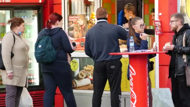 Los jóvenes compran shawarma y otras comidas rápidas en un quiosco callejero. Chico y chica — Vídeos de Stock