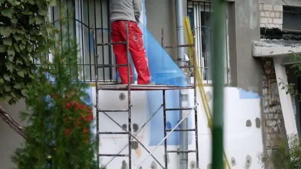 인부들은 벽돌 집 밖에 단열재를 설치하여 아파트를 절연 시킨다 — 비디오