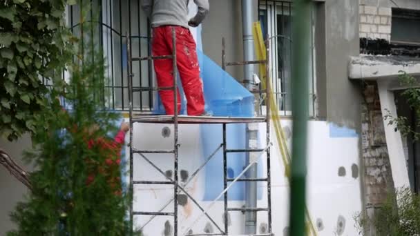 Workers insulate an apartment by installing insulation outside brick house — Stock Video