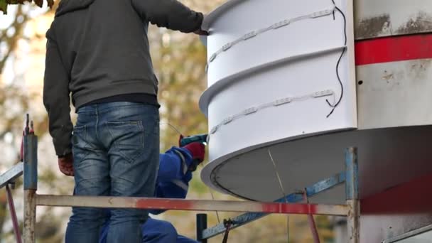 노동자들이 헬스 장 입구 위에 LED 조명을 비추는 옥외 광고를 설치하는 모습 — 비디오