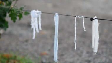 Beyaz ipler ön bahçenin yakınındaki bir telden sarkıyor. Beyaz paçavralar ya da bant parçaları