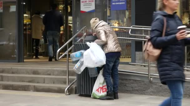 Street scene near supermarket. Ederly homeless woman with two plastic bags — Stock Video