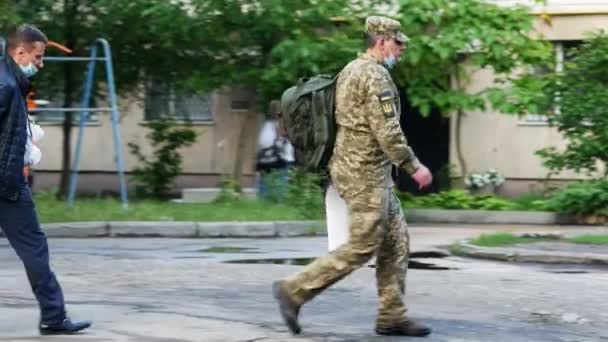 Ένας στρατιωτικός περπατάει κατά μήκος ενός δρόμου της πόλης. Ουκρανός στρατιώτης πηγαίνει σπίτι του — Αρχείο Βίντεο