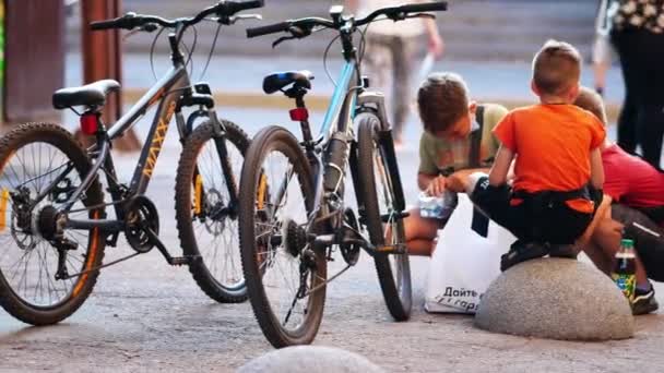 Jungen essen an warmen, sonnigen Sommertagen neben ihren abgestellten Fahrrädern auf dem Gehweg — Stockvideo