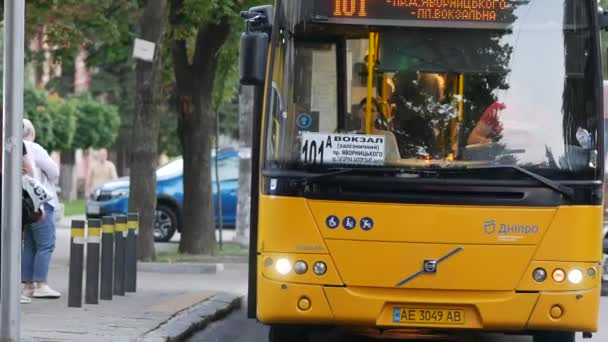 Mladá žena chce chytit velký žlutý autobus Volvo s pasažéry na autobusové zastávce — Stock video