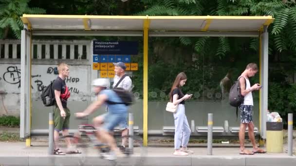 La gente si trova ad una fermata dell'autobus in attesa che arrivino i mezzi pubblici — Video Stock