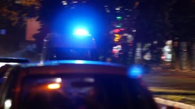 Parlayan fenerleri olan bir ambulans arabası geceleri şehrin caddesinde koşuşturuyor.