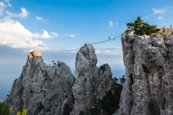 ヤルタの上に歯をロック - .崖の上とクロスウクライナの登山家の上にウクライナ人は、開発極端な観光のための橋を引っ張った. ロイヤリティフリーのストック写真