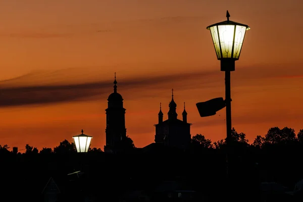 Het silhouet van een orthodoxe kerk tegen de achtergrond van een stralende gouden heldere oranje lucht. — Stockfoto