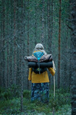 KARELIA, RUSSIA - 6 Haziran 2020: Sırt çantalı kız çam ormanında duruyor