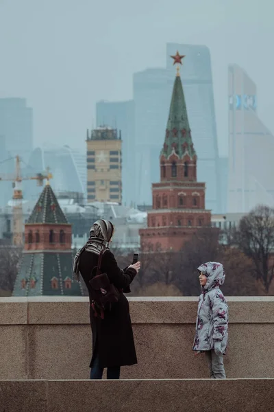 MOSCOW, Ryssland - NOVEMBER 14 2020: Mamma fotograferar barnet på en smartphone på Bolsjoj Moskvoretskij-bron — Stockfoto