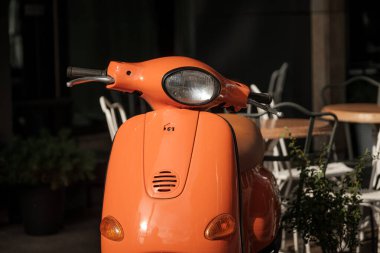 Güneşli bir günde dışarıda duran turuncu scooter..