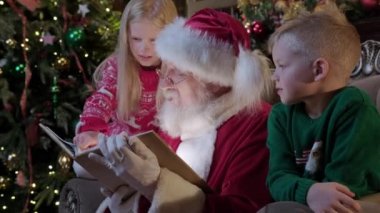 Noel Baba, Noel ağacının ve şöminenin arka planında oturan çocuk ve kız çocuklarına yeni yıl masalı okur. Noel Baba onlarla evde oynayan çocukları ziyaret ediyor.
