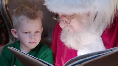 Uzun, gri sakallı yaşlı adam Noel Baba, küçük sarışın çocuğa Noel hikâyesi okur. Odada şömineli ve Noel ağacı süslenmiş bir şekilde oturur. Yeni yıl tatili kavramı.