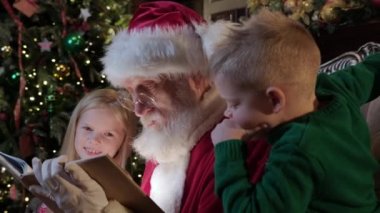 Gri sakallı yaşlı adam Noel Baba kitaptan kıza peri masalı okur. Yüzlerinde kitaptan parlak bir ışık parıldar. Yeni yıl peri masalı, Noel 'de büyülü ruh hali.