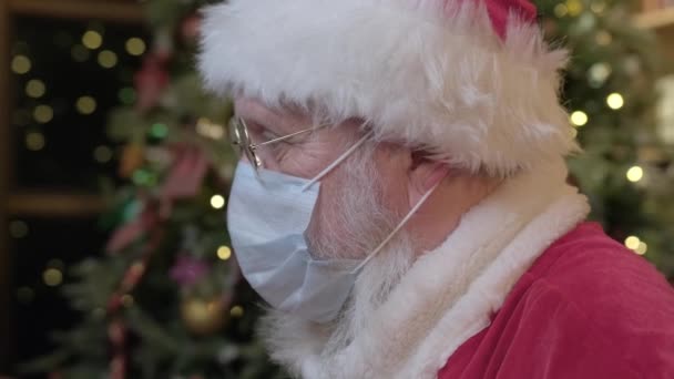 Babbo Natale stanco rimuove la maschera medica dal viso ed espira aria dai polmoni con sollievo. Libertà dalla pandemia di coronavirus. Malato Babbo Natale infettato da baccalà 19 si toglie la maschera, guarda avanti. — Video Stock