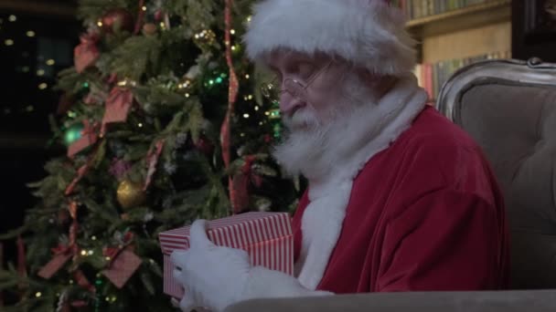 Jultomten öppnar magiska glödande presentförpackning och ser inuti, starkt ljus lyser från lådan. Julafton med magiska gåvor från Sankt Nikolaus. Gott nytt år och jul. — Stockvideo