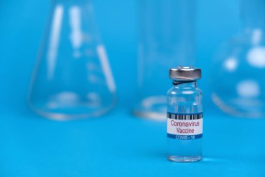 Covid-19 Coronavirus aşısı konsepti. Arka planda tıbbi gereçlerle birlikte mavi masada metal kapaklı cam şişeler. 2019-NCoV virüsüne karşı aşı. Salgın SARS-NCoV karşısında zafer.