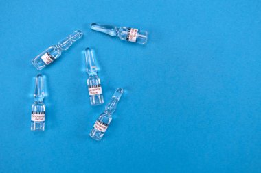 Hazır Covid19 aşısı olan cam ampuller mavi üzerine uzanır, yukarıdan gelen metin görüntüsü için boşluk ile birlikte. İnsanları aşılama ve SARS-NCov salgınıyla mücadele kavramı. 2019-NCoV İcat Aşısı