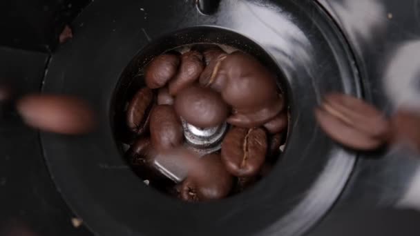 Nahaufnahme geröstete Arabica-Kaffeebohnen werden mit den eisernen Messern einer elektronischen Kaffeemühle in Nahaufnahme gefüllt und gemahlen, um heißen, aromatischen schwarzen Americano-Kaffee von oben herzustellen.. — Stockvideo