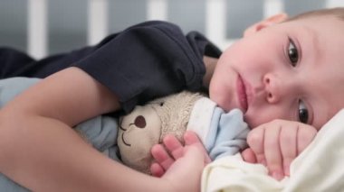 Depresyonda olan ve anne ve babasının desteği olmadan yatakta yatıp oyuncak ayıyı kucaklayan kendine yeten küçük bir çocuk. Kendini soyutlama ve psikolojik bozukluk kavramı.